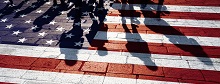 Decorative image of an American flag painted on bricks with shadows of people on it