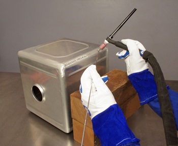 Welder using a block to support hands for TIG welding